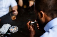 Rear view of man lighting up the cigarette in his mouth