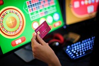 A gambler&#39;s hand holding a credit card playing an online gamble