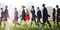 Group of diverse business people walking on a meadow in a cityscape background