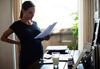 A pregnant woman reading notes and drinking milk