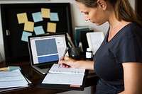 Pregnant woman is working and writing important notes