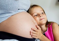 Excited young girl listening to her pregnant mother belly