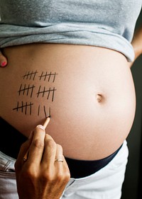 Father marking pregnancy due date on a woman’s baby bump