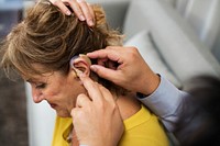 A doctor inserting hearing aid to a patient's ear