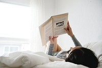 An Asian Woman Reading on a Bed in a Bright Minimal Room