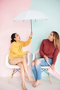 Women friends sitting in living room with umbrella 