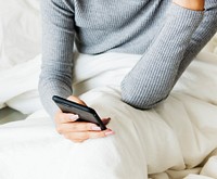 An Asian Woman Using a Mobile Phone on a Bed