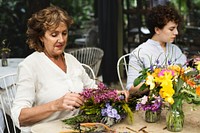 Women arranging flowers together at the table
