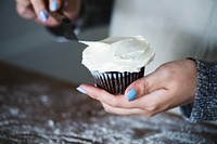 Woman frosting a cupcake