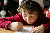 Caucasian kid writing a Christmas wishlist
