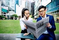 Asian business people reading the newspaper