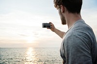 Caucasian man taking a photo of the sunset