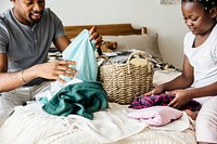 Dad and daughter folding clothes in bedroom together