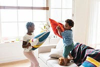 Brother and sister pillow fighting in living room