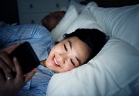 Asian woman using phone on a bed