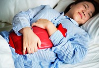 A woman in pain holding a hot water bottle