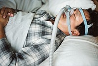 A man sleeping with anti snoring chin strap