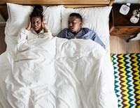 African American couple on bed, man snoring and disrupting woman&#39;s sleep
