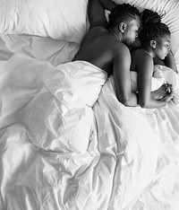 Black and white photo of African descent couple sleeping on the bed snuggling and hugging