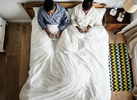 African American couple on bed using cellphones