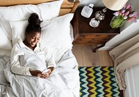 Smiling African American woman on bed using a cellphone