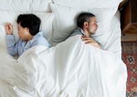Interracial couple sleeping back to back on the bed