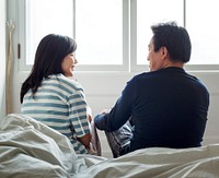 Asian couple talking together in bed