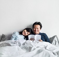 Asian couple relaxing on bed together