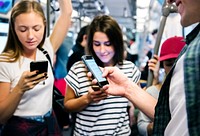 Group of young adult friends using smartphones in the subway