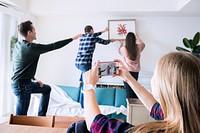 Young group of friends decorating the apartment and a woman taking a photo