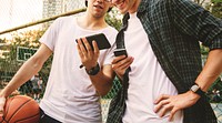 Young adult male friends on the basketball court using smartphones millennials concept