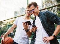 Young adult male friends on the basketball court using smartphones millennials concept