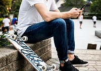 Young adult skateboarder using a smartphone youth culture concept