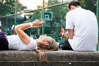 Young woman lying down in the park using a smartphone