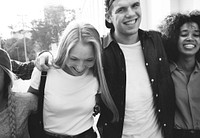 Smiling happy young adult friends arms around shoulder walking outdoors