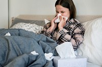 Sick woman sneezing in bed
