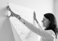 White architect showing building plan on white wall