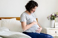 Pregnant woman sitting on the bed<br />