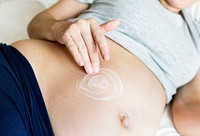 Pregnant woman applying body cream on baby bump