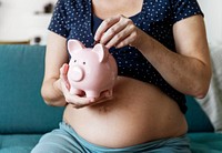 Pregnant woman saving money in piggy bank