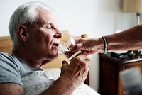 Caucasian senior man drinking water in his bed