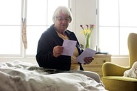 Senior woman sitting on the bed and looking at photos