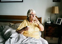 Senior woman having pills on her bed