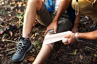 Man putting bandage on his partner&#39;s knee in the jungle