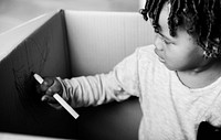 Young black boy drawing in a box
