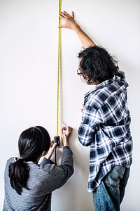 Asian couple measuring the wall