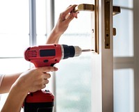 Woman using electronic drill installing door