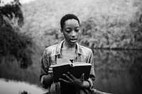 African American woman alone in nature reading a book leisure concept