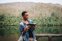 African American woman alone in nature reading a book leisure concept