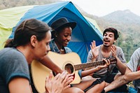 Group of young adult friends in camp site playing guitar and ukelele and singing together outdoors recreational leisure and friendship concept